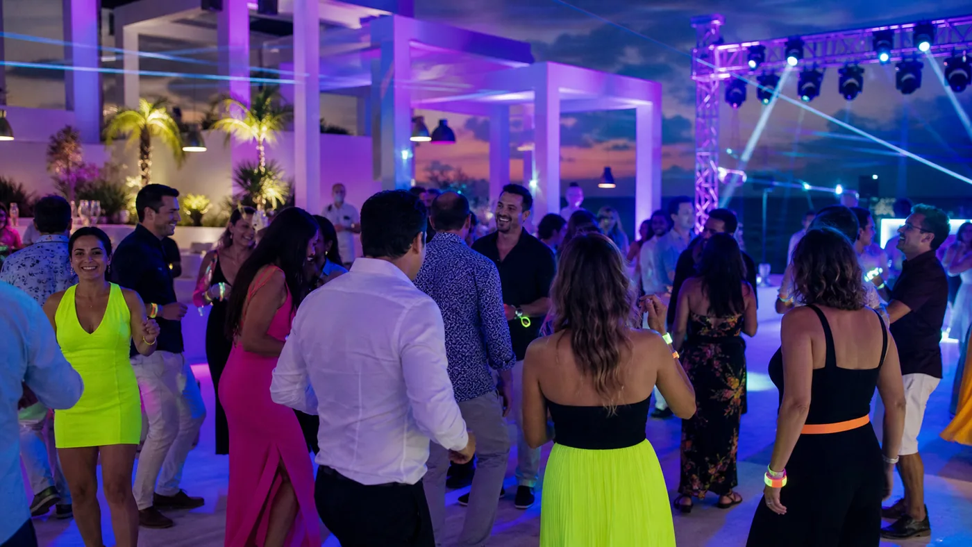 Adultos bailando durante una fiesta neón en la terraza de un resort de Cancún