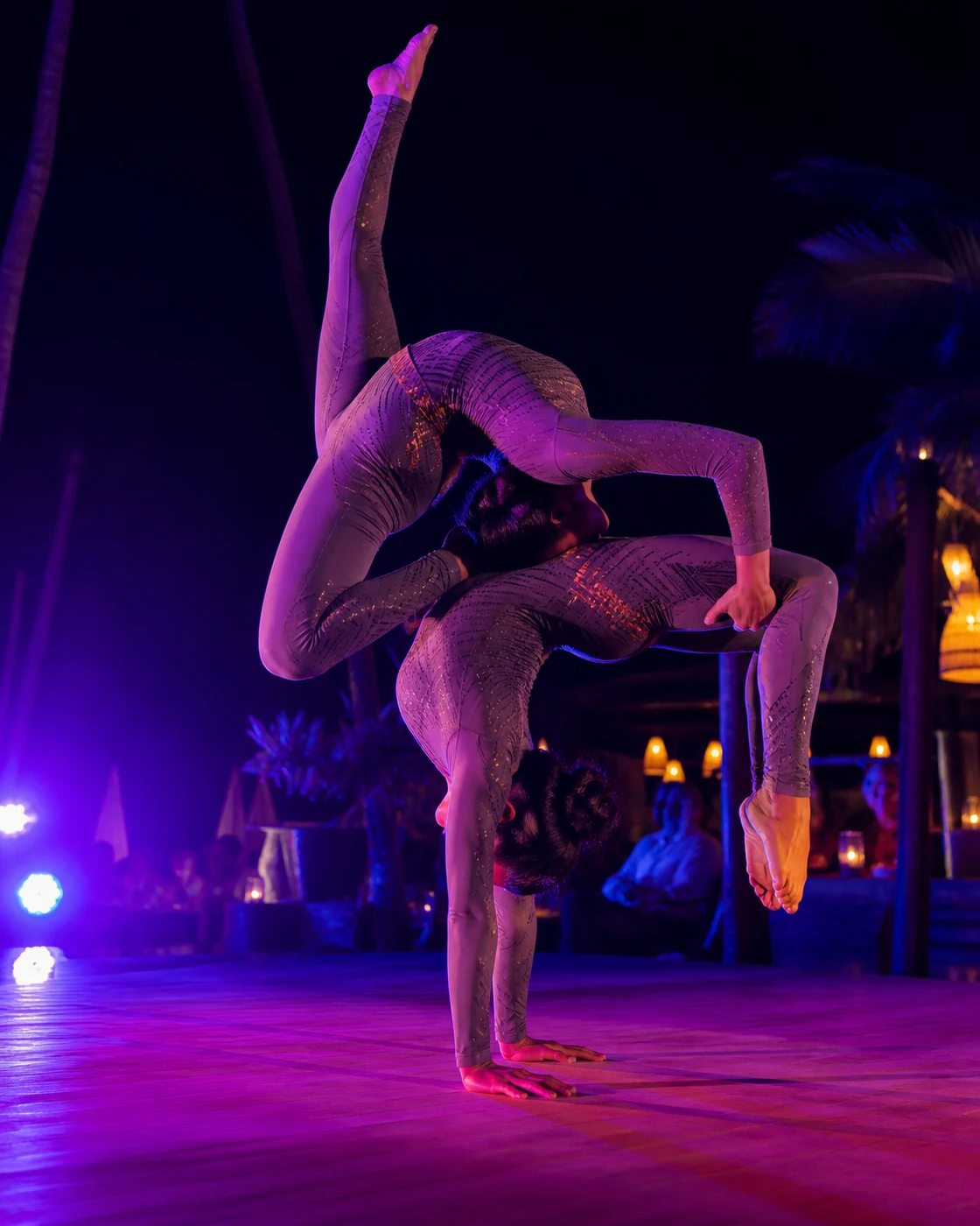 Dos artistas de acrobacia durante un show nocturno con iluminación violeta