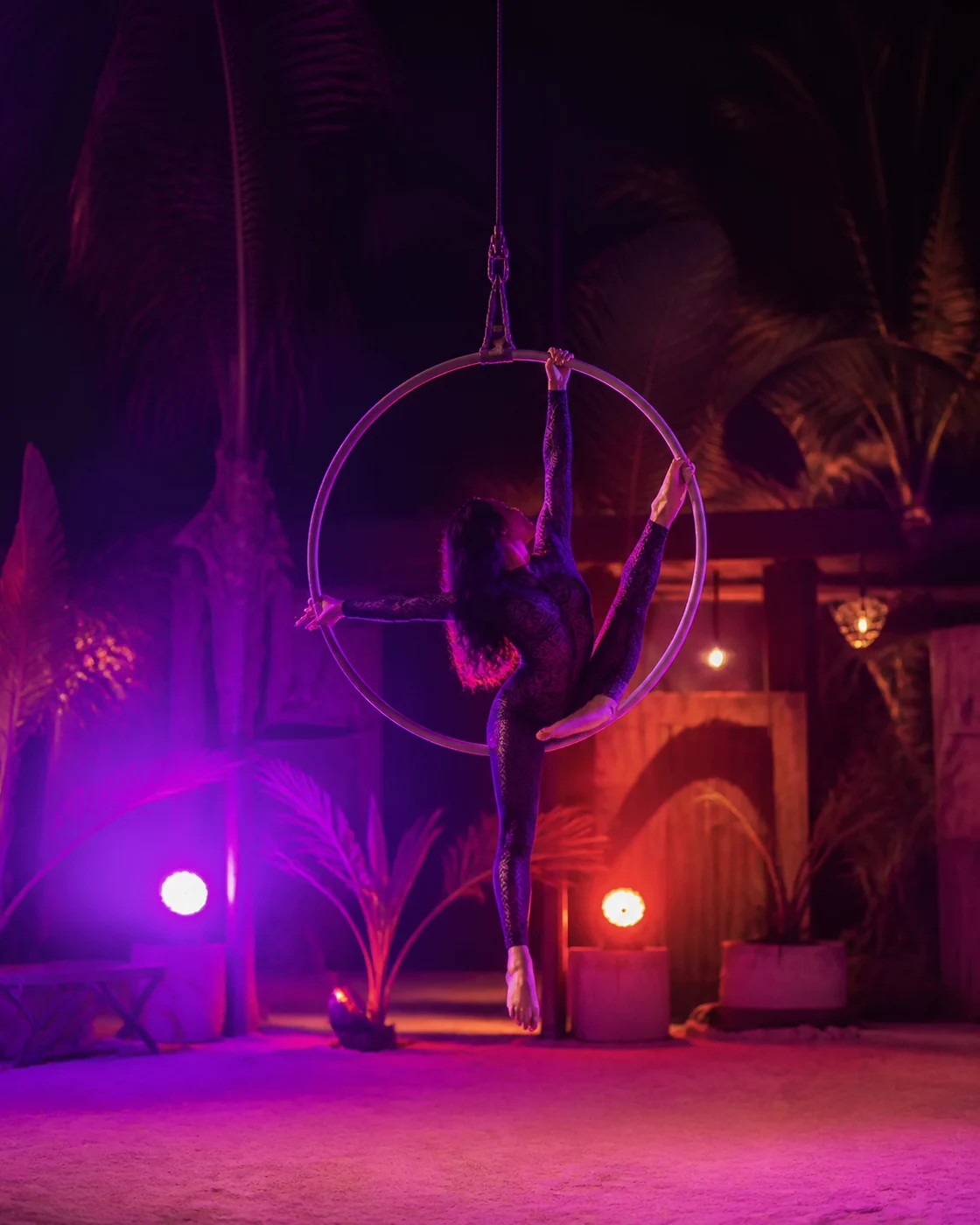 Artista en un aro aéreo durante un show nocturno al aire libre